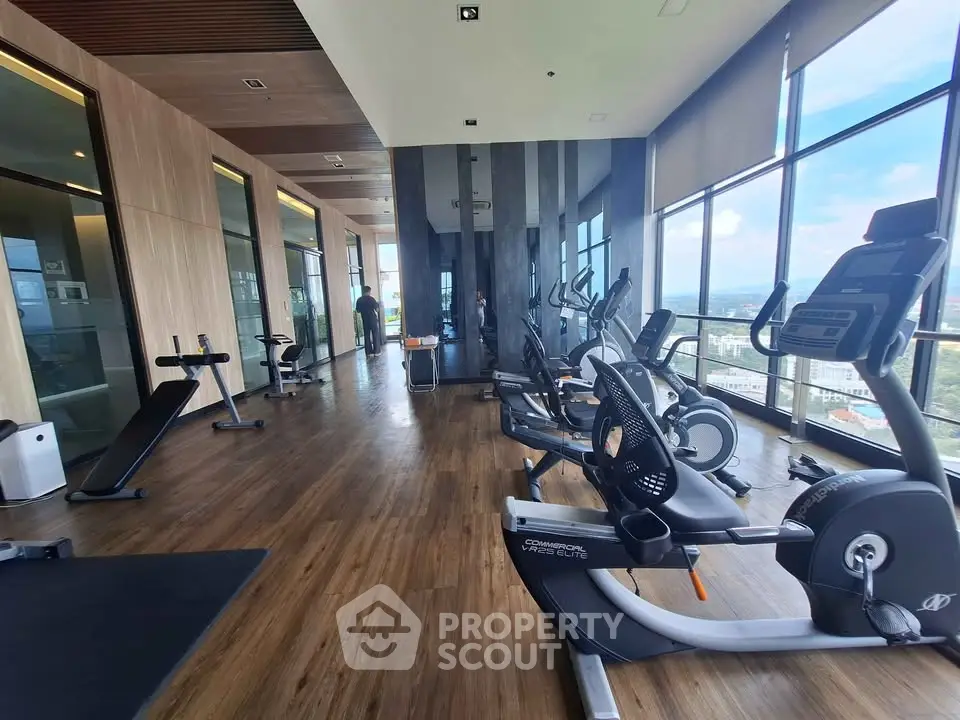 Spacious modern gym with panoramic city views and state-of-the-art fitness equipment.