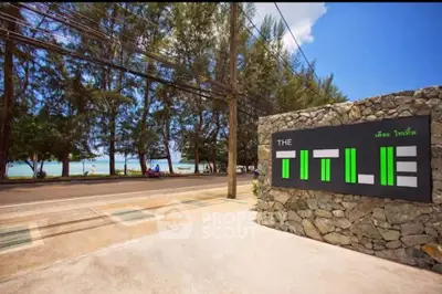 Beachfront property entrance with modern stone signage and lush surroundings.