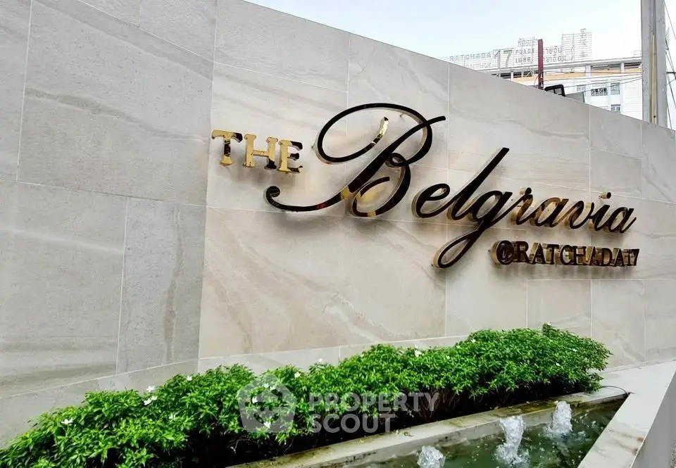 Elegant entrance sign of The Belgravia with lush greenery and water feature.