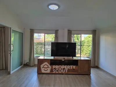 Spacious living room with large windows and modern TV setup