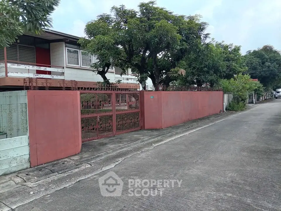 Charming residential property with gated entrance and lush greenery on a quiet street.
