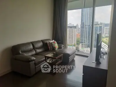 Modern living room with city view, featuring a sleek leather sofa and large windows.