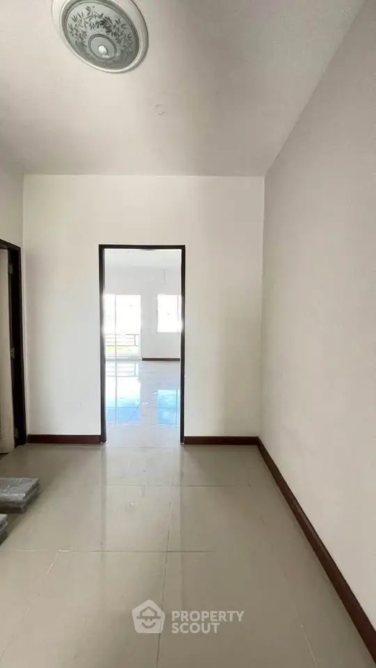 Spacious hallway leading to a bright living area with large windows.