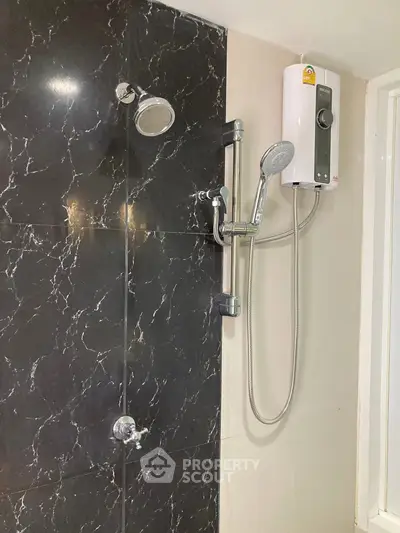 Modern bathroom shower with sleek black marble wall and water heater.