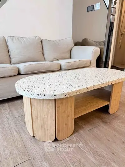 Stylish living room with modern terrazzo coffee table and cozy beige sofa.