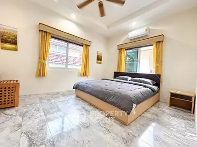 Spacious bedroom with modern decor and large windows in a luxurious home.