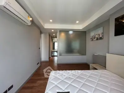 Spacious modern bedroom with wooden flooring and air conditioning in a stylish apartment.