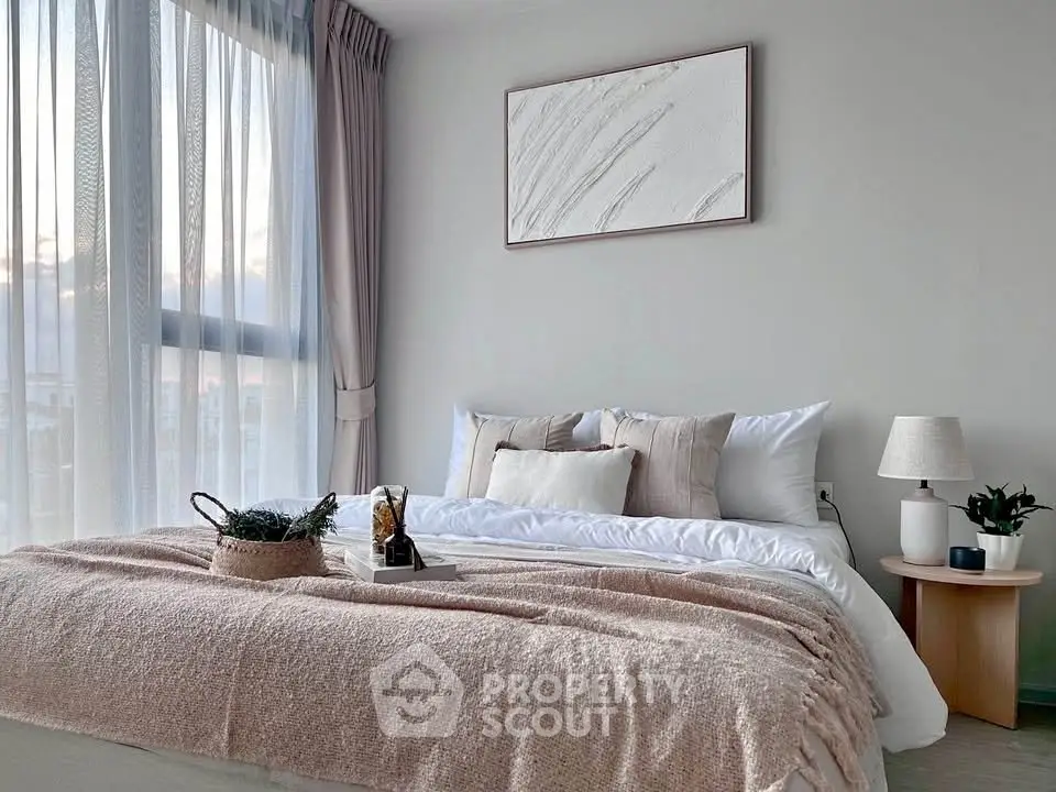 Elegant bedroom with large window, cozy bedding, and stylish decor in modern apartment.