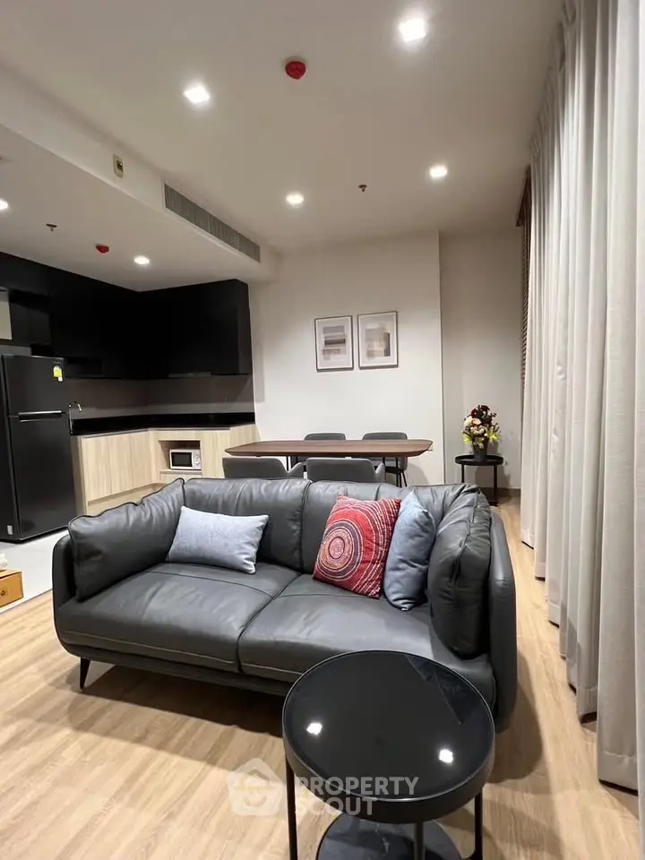 Modern living room with sleek black sofa and open kitchen layout, perfect for contemporary living.