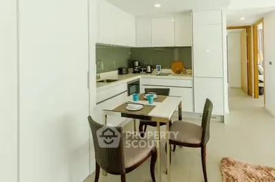 Modern kitchen with sleek white cabinets and cozy dining area in a stylish apartment.