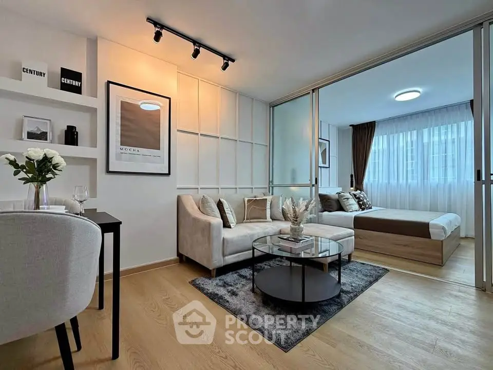 Modern open-plan living room with stylish decor and sliding glass doors to bedroom.
