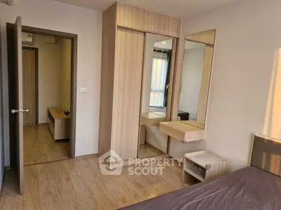 Modern bedroom with wooden flooring and built-in wardrobe, featuring a minimalist design and ample natural light.