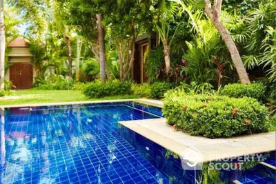 Luxurious tropical garden with sparkling blue pool and lush greenery