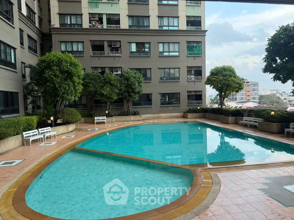 Luxurious residential building with a stunning pool and lush greenery.