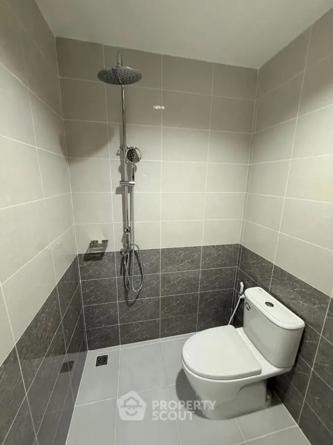 Modern bathroom with sleek shower and toilet in neutral tones.