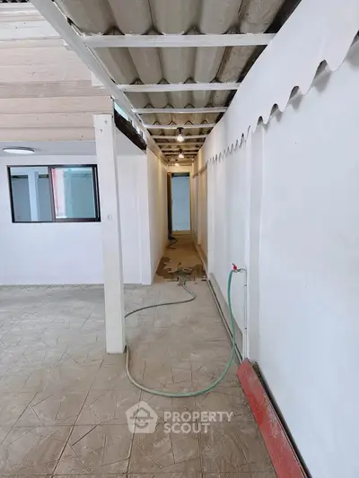 Spacious corridor with rustic ceiling and tiled floor, perfect for renovation opportunities.