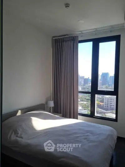 Modern bedroom with city view, large window, and cozy ambiance in urban apartment.