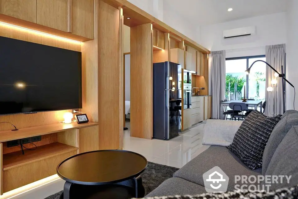 Modern living room with open kitchen, sleek furniture, and large TV in stylish apartment.