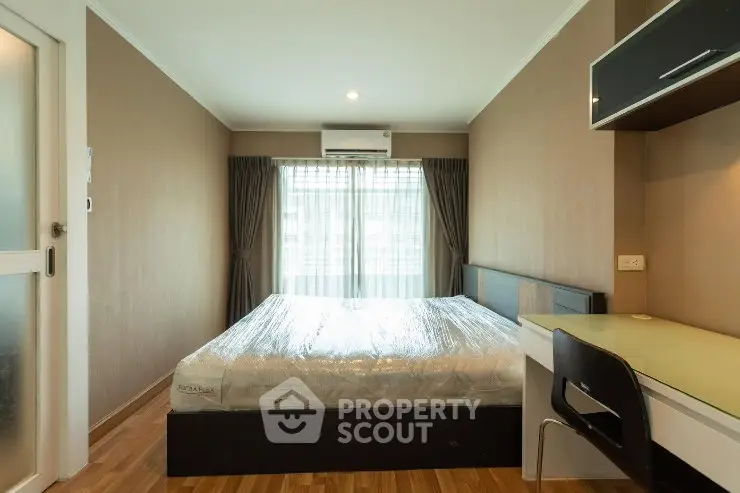 Modern bedroom with natural light, featuring a comfortable bed and sleek workspace.