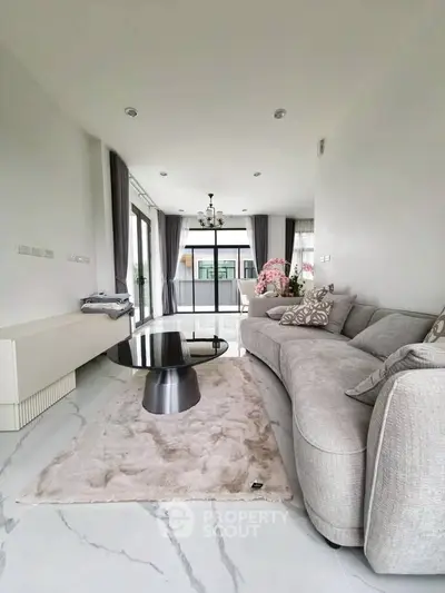 Luxurious modern living room with elegant decor and large windows offering natural light.