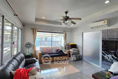 Spacious living room with modern ceiling fan and large windows for natural light.
