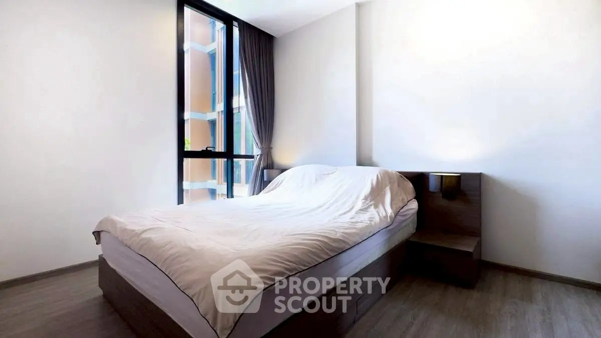 Modern minimalist bedroom with large window and sleek wooden furniture.