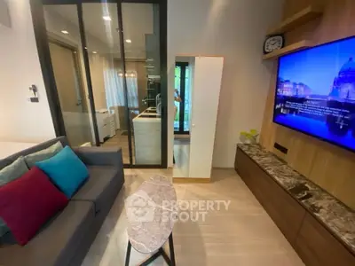 Modern living room with stylish decor and open kitchen layout, featuring a cozy sofa and wall-mounted TV.