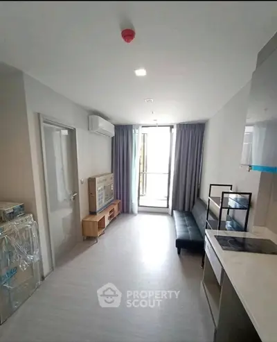 Modern apartment interior with compact living room and kitchen, featuring sleek furniture and natural light.