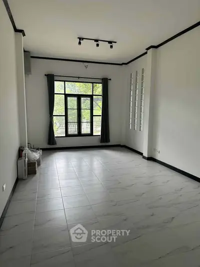 Spacious empty living room with large window and elegant tile flooring