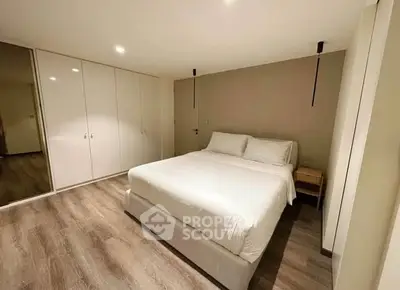 Spacious modern bedroom with elegant wooden flooring and ample closet space.