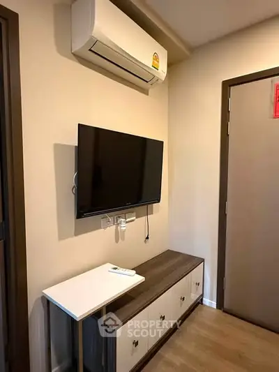 Modern living room with wall-mounted TV and air conditioning unit, featuring sleek storage cabinet.