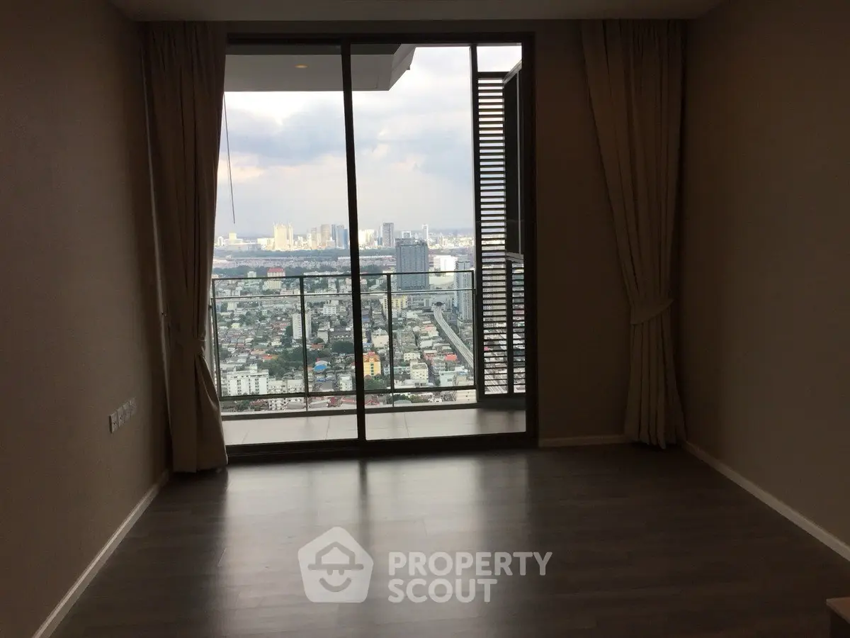Spacious apartment with floor-to-ceiling windows offering stunning cityscape views from a high-rise balcony.