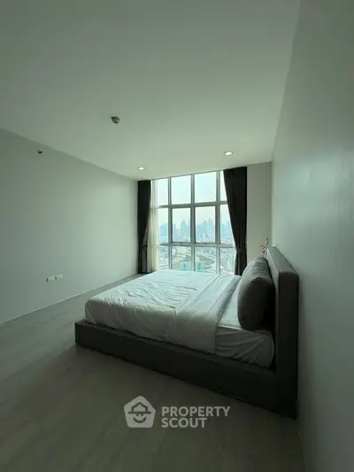 Spacious bedroom with large windows offering stunning city views.