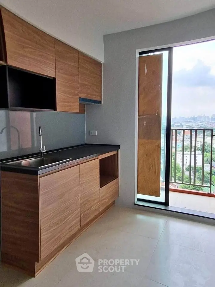Modern kitchen with sleek wooden cabinets and city view from balcony.