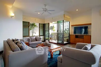 Spacious living room with modern furniture and large windows opening to a balcony with city views.