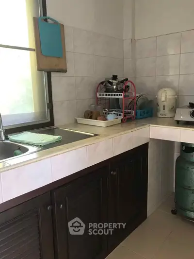 Cozy kitchen with tiled backsplash and essential appliances, perfect for home cooking.