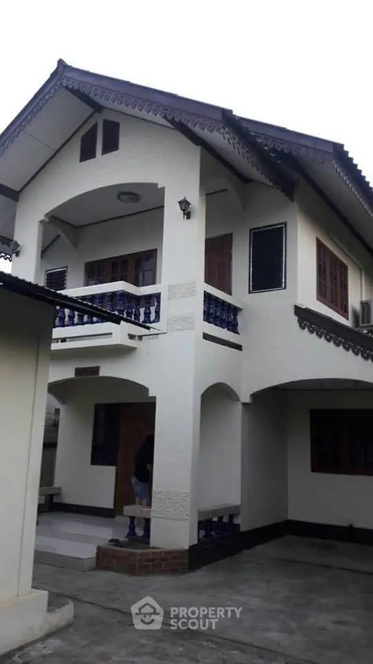 Charming two-story home with traditional design, featuring a spacious balcony with intricate railings, large windows, and a welcoming entrance.