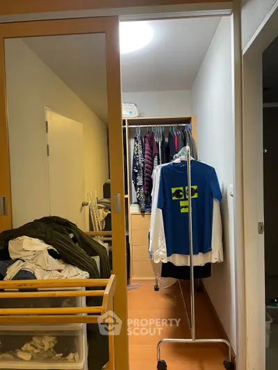 Spacious walk-in closet with ample storage and hanging space, featuring wooden flooring and sliding doors.