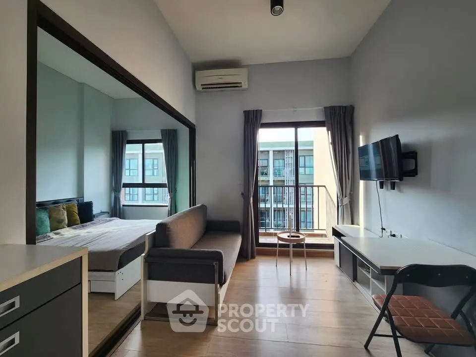 Modern studio apartment with balcony and city view, featuring sleek furnishings and ample natural light.
