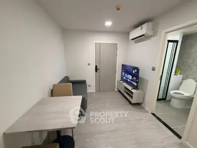 Modern living room with sleek furniture and open layout, featuring a wall-mounted TV and air conditioning.