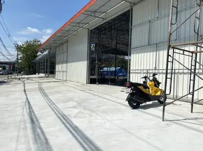 Spacious industrial warehouse under construction with ample parking space and modern design.