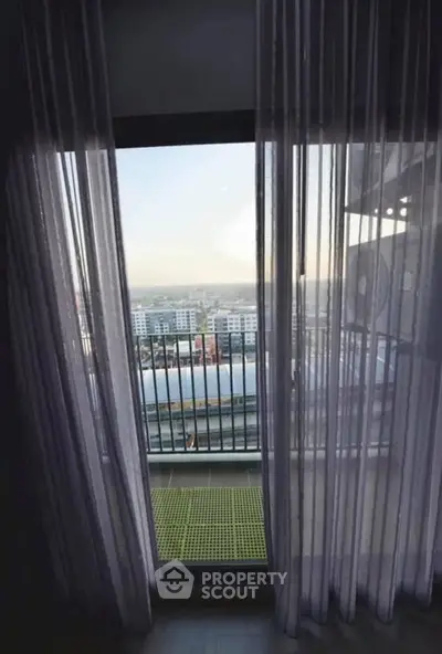 Stunning balcony view from modern apartment with sheer curtains and cityscape.