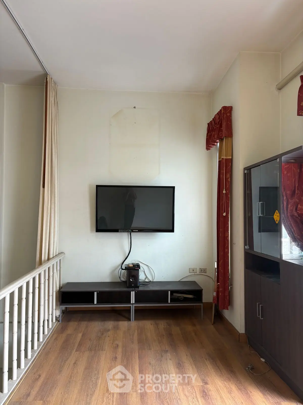 Cozy living room with mounted TV and wooden flooring, perfect for relaxation.