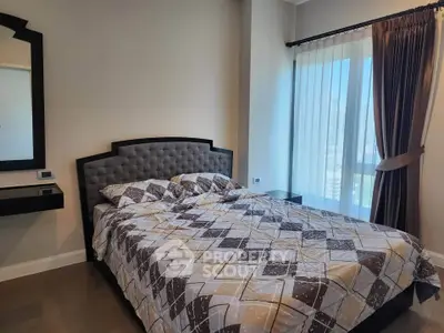 Spacious bedroom with modern decor and large window offering natural light.