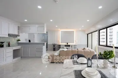 Spacious open-plan living room and kitchen with modern decor and large windows.