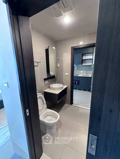 Modern bathroom with sleek fixtures and view into contemporary kitchen