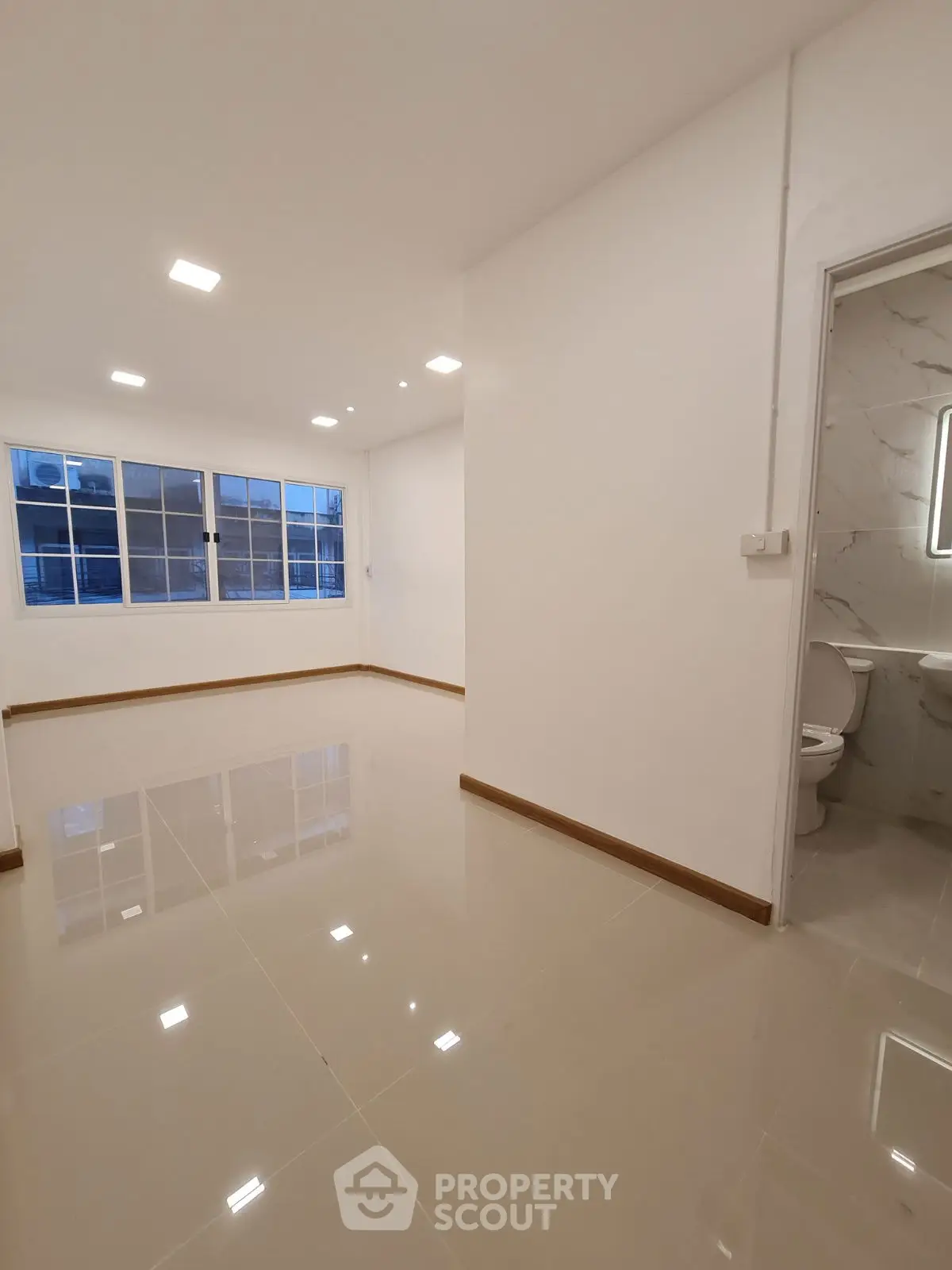 Spacious modern living room with glossy tiled floors and large windows