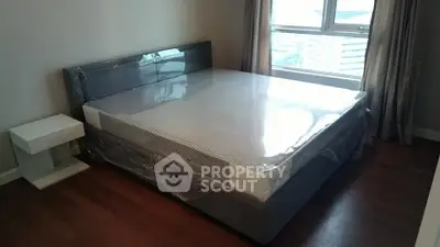 Modern bedroom with large window and sleek furniture in urban apartment.