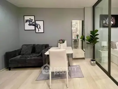 Modern living room with sleek decor and glass partition leading to bedroom.