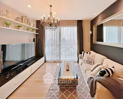 Elegant living room with chandelier, large TV, and cozy decor in modern apartment.